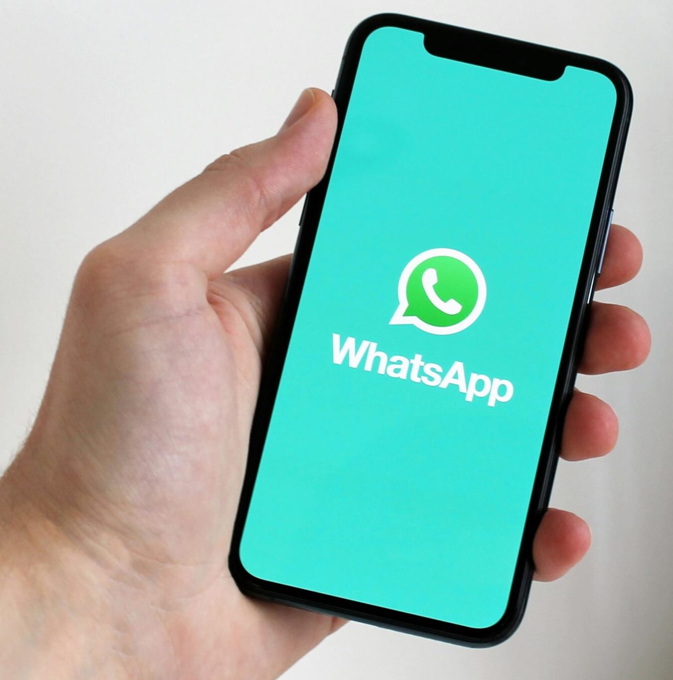 Close-up of a hand holding a smartphone displaying the WhatsApp app screen.